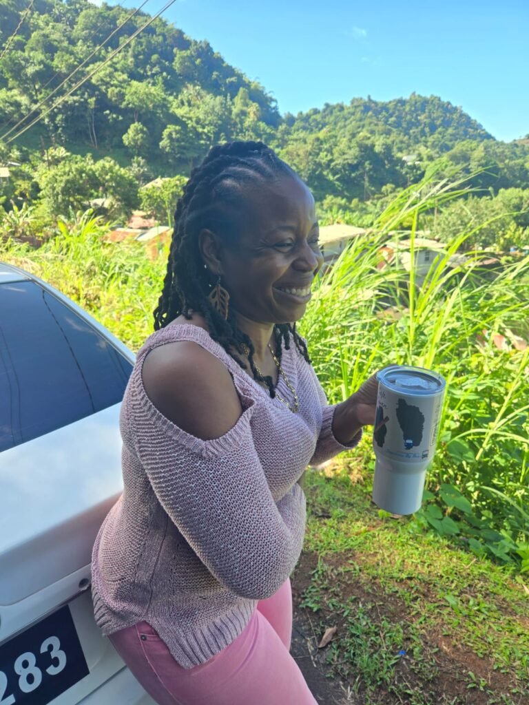 Woman with a Coffee Cup Smiling with mountains in the backdrop in Campbell, Dominica.